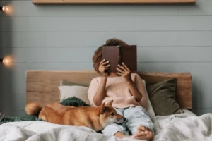 A person relaxing with a dog, indicating a pet sitter. One of the most popular side hustle job ideas is a pet sitter.
