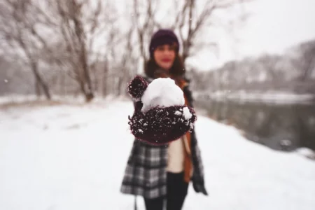 Woman holding a snowball, symbolizing the debt snowball method for tackling credit card debt, taking small steps towards financial freedom.
